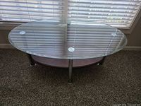 Oval glass coffee table front view showing glass top, wood shelf, chrome legs