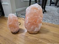 Both Himalayan salt lamps side by side on floor showing relative sizes and corded bases