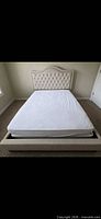Full view of assembled beige upholstered queen bed, mattress in place