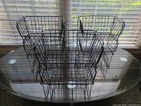 Four black wire shelf risers on glass table