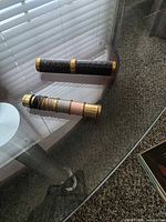 Two brass cylindrical tubes on glass table