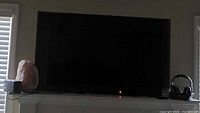 Front view of Vizio TV on mantle, screen off, red standby light visible