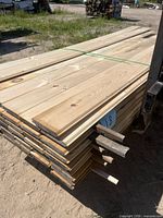 Top view of strapped bundle of white pine boards showing grain and weathered edges