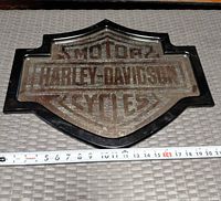 Front view of Harley-Davidson shield plastic wall sign with measuring tape showing width