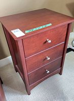 Front view of wooden three-drawer bedside table