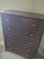 Front view of dark brown 5-drawer dresser with silver knobs