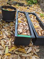 Two of the black resin rectangular planters side by side with leaves inside