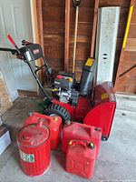 Side view of Craftsman snow blower and four fuel cans