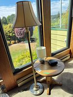 Brass floor lamp, side table with table lamp and clock radio by window