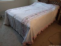 Bedspread on full bed, showing floral embroidered sides and ruffle hem
