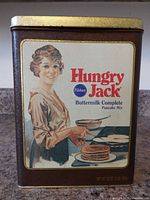 Front view of Hungry Jack pancake mix tin showing main graphic and branding