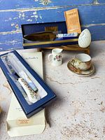 Group shot of all items including boxed knife, boxed server, teacup & saucer, creamer and decorative egg