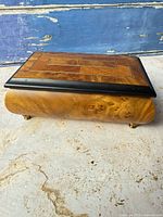 Side profile showing curved burl wood grain and gold feet