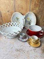 Group shot showing all eight pieces: reticulated bowl, divided floral dish, red cup and saucer, two demitasse cups and saucers