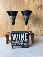 Two black martini glasses on wood stand with wine quote sign in front