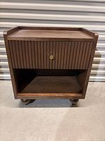 Front view of nightstand showing drawer, shelf, tray top, bun feet