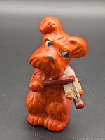 Front view of orange dog figurine holding violin