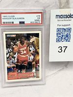 Front view of PSA-slabbed 1993 Fleer Olajuwon card with MaxSold lot number visible