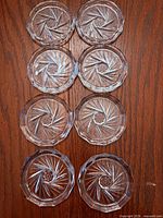 All eight clear pressed glass coasters arranged to show pinwheel pattern and condition