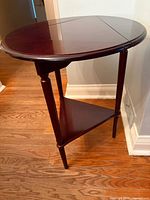 Side view showing round top with one drop leaf extended and lower triangular shelf