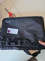 Front view of black nylon laptop bag with handles and strap