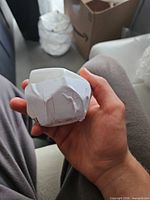 White faceted ceramic candle holder wrapped in protective paper held in hand