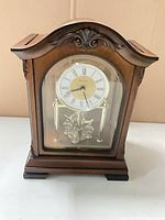 Front view of Bulova wood mantel clock showing dial, bezel and pendulum