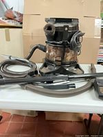 Canister vacuum on dolly with hose and wands visible