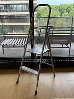 full view of folded aluminum two-step ladder standing on floor