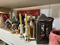 Shelf showing nativity set, candle holders, pillar candles, metal lantern and garland