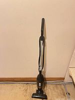Full view of black Bissell corded stick vacuum standing upright