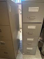 Front view of gray 4-drawer metal filing cabinet alongside another cabinet