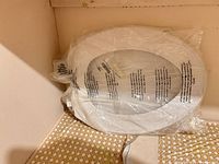 sealed white round plastic toilet seat leaning against wall
