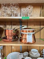 Four copper cookware pieces on shelf