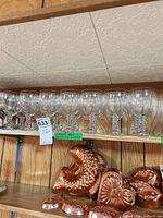 Eight clear glass goblets lined on shelf