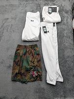 Overview of three white Under Armour pants and one camo Jordan shorts