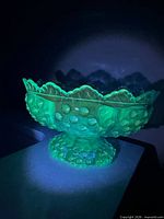 Compote glowing green under UV light showing hobnail pattern and scalloped rim