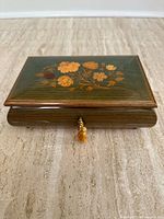 Closed box showing green marquetry lid, brass key with tassel