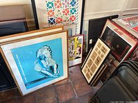 Group shot of stacked framed artworks showing variety of prints and frames