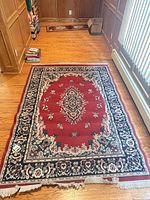Full view of red floral bordered area rug on hardwood floor