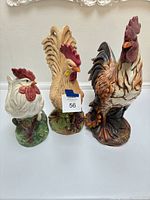 Front view of all three rooster figurines side by side