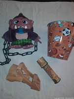 Group shot of plush monster with chain, wooden catapult, kaleidoscope, and sports bucket
