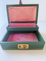 Jewelry box open showing pink velvet interior, removable tray and ring rolls