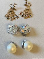 All three pairs of earrings displayed: gold-tone star dangle, crystal cluster, faux pearl