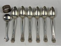 Full lot showing ladle, napkin ring, six teaspoons