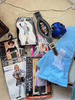 Group of packaged costumes, belt, hat and blue fabric piece laid out