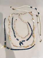 All five necklaces laid out showing overall design and closures