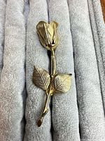 Full view of gold-tone rose brooch showing stem, leaves and bud