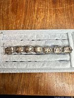 Full view of bracelet laid flat showing all seven engraved panels and filigree work