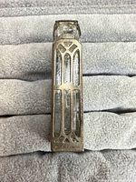 Front view of rectangular sterling silver perfume vial pendant showing filigree design and glass insert